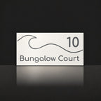 Matte white house number and street name sign, The Moffat, reading 10 Bungalow Court in charcoal lettering, with a wave.