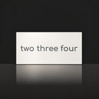 Matte white house number sign, The Montville, with the number spelled out as two three four in charcoal lettering.