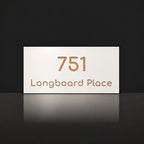 Brushed copper house number and street name sign with a brushed metal look, The Peregian, white face reading 751 Longboard Place in copper lettering.
