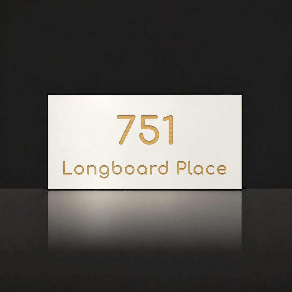 Brushed gold house number and street name sign with a brushed metal look, The Peregian, white face reading 751 Longboard Place in gold lettering.