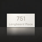 Brushed silver house number and street name sign with a brushed metal look, The Peregian, white face reading 751 Longboard Place in silver lettering.