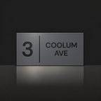 Matte charcoal house number and street name sign, The Coolum, reading 3 Coolum Ave in black lettering, with a dividing line.