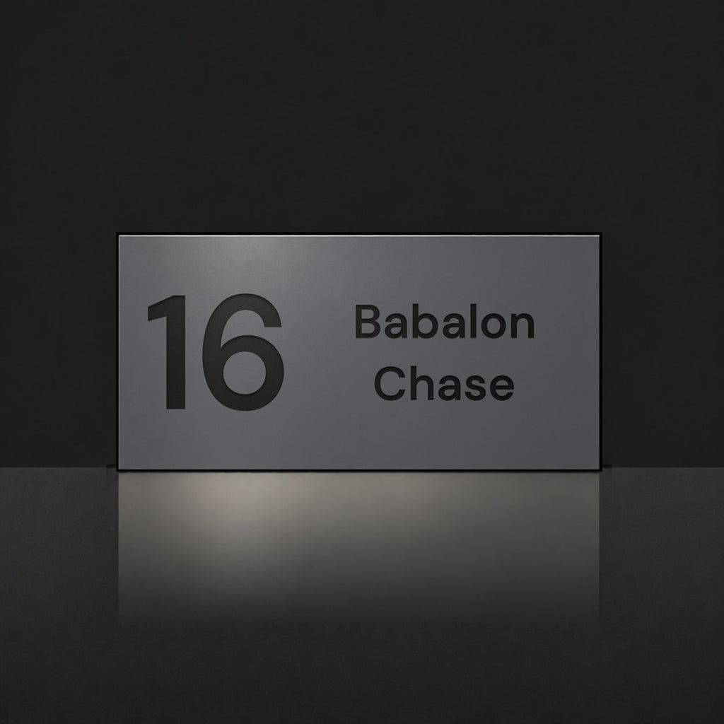 Matte charcoal house number and street name sign, The Marcoola, reading 16 Babalon Chase in black lettering.