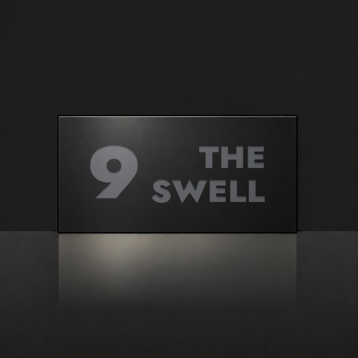 Matte black house number and street name sign, The Marcoola, reading 9 The Swell in charcoal lettering.