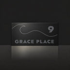 Matte black house number and street name sign, The Moffat, reading 9 Grace Place in charcoal lettering, with a wave.