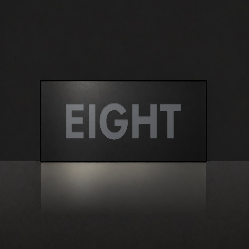 Matte black house number sign, The Montville, with the number spelled out as eight in charcoal lettering.