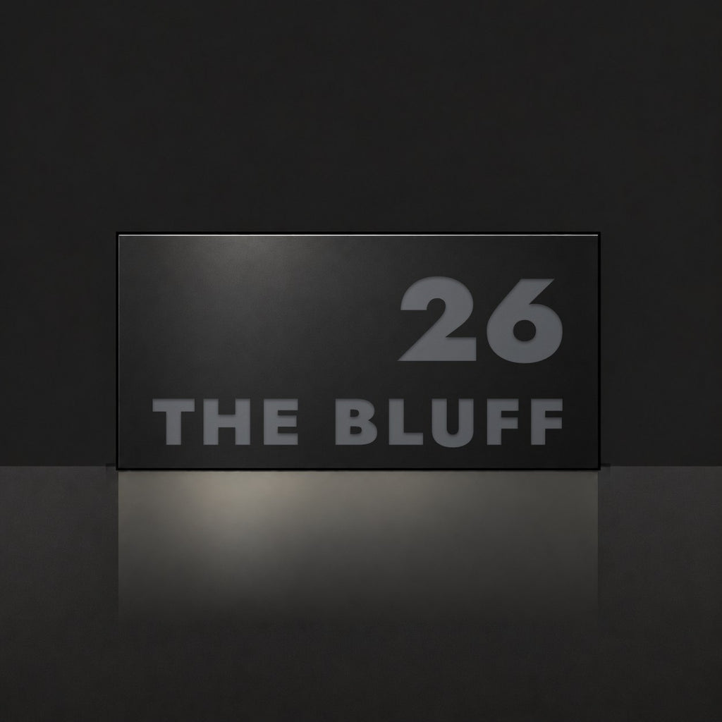 Matte black house number and street name sign, The Peregian, reading 26 The Bluff in charcoal lettering.