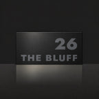 Matte black house number and street name sign, The Peregian, reading 26 The Bluff in charcoal lettering.