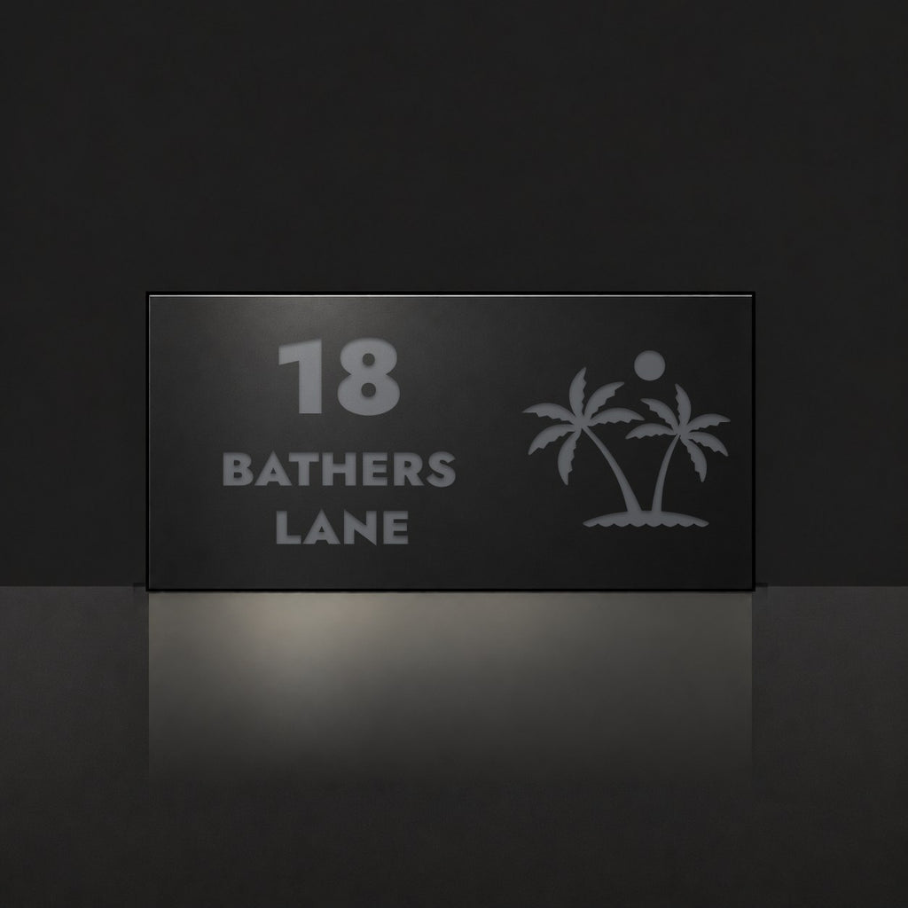 Matte black house number and street name sign, The Yaroomba, reading 18 Bathers Lane in charcoal lettering, with palm trees and a sun.