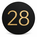 Black round house number sign with the number 28 in gold, The Caloundra style, on a plain white background.