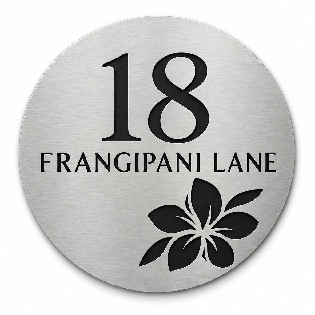 Brushed silver round house number and street name sign reading 18 Frangipani Lane with a frangipani flower cut through to black, The Currimundi style, on a plain white background.