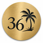 Brushed gold round house number sign with the number 36 and a palm tree cut through to black, The Mooloolaba style, on a plain white background.