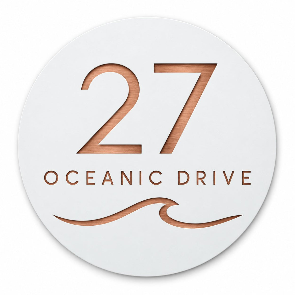 White round house number and street name sign reading 27 Oceanic Drive with a curling wave, cut through to brushed copper, The Mudjimba style, on a plain white background.