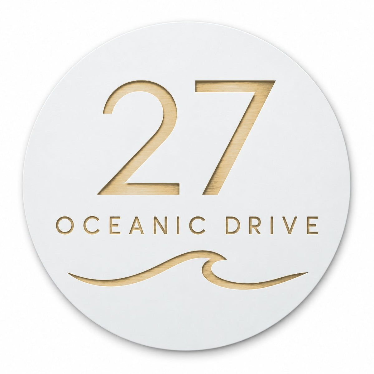 White round house number and street name sign reading 27 Oceanic Drive with a curling wave, cut through to brushed gold, The Mudjimba style, on a plain white background.