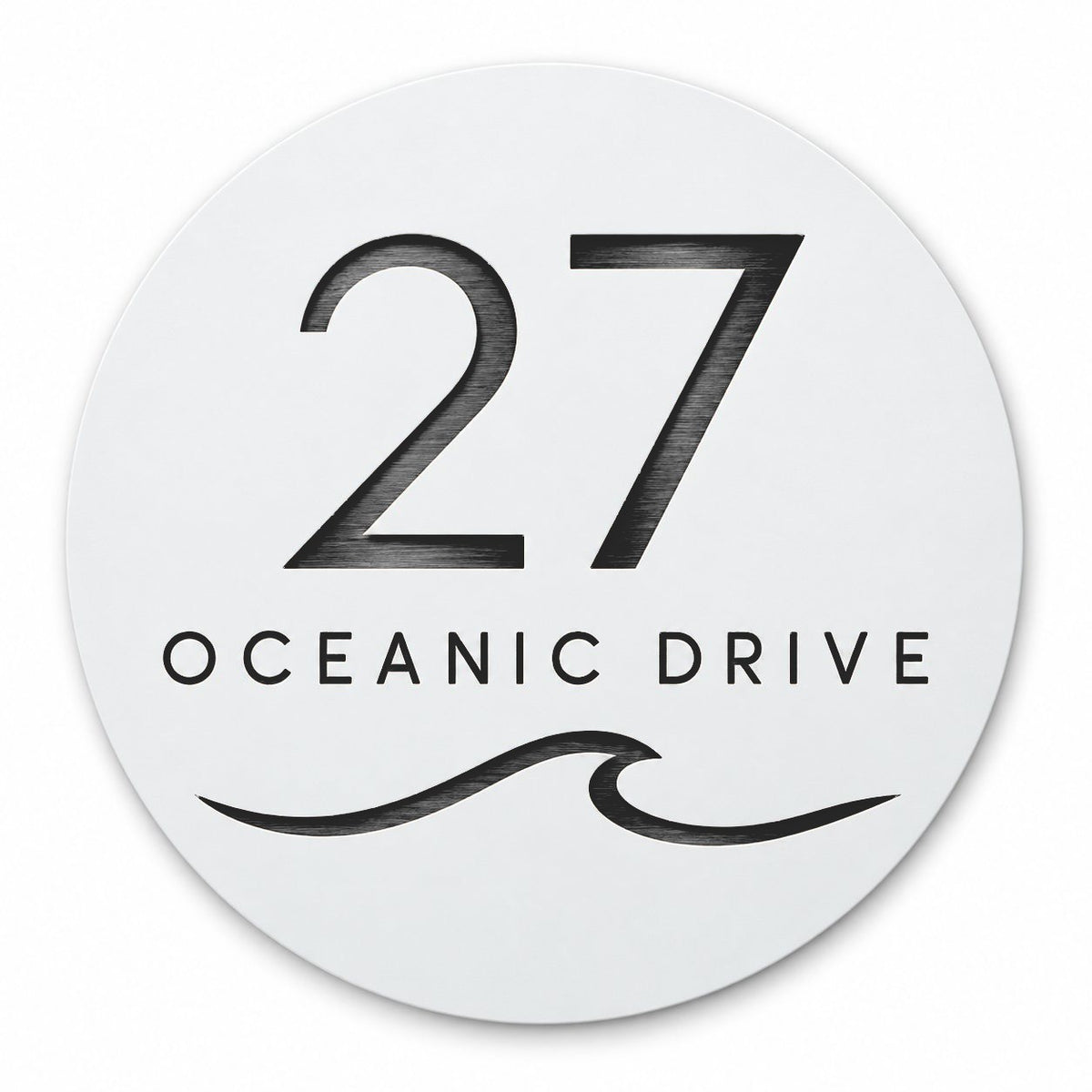 Matte white round house number and street name sign reading 27 Oceanic Drive with a curling wave, cut through to black, The Mudjimba style, on a plain white background.